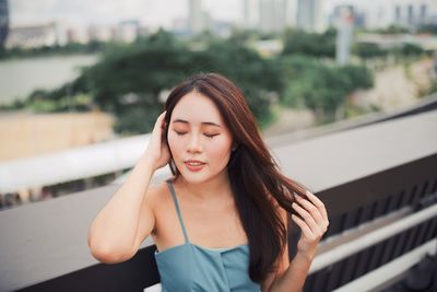 Beautiful young woman with eyes closed by railing