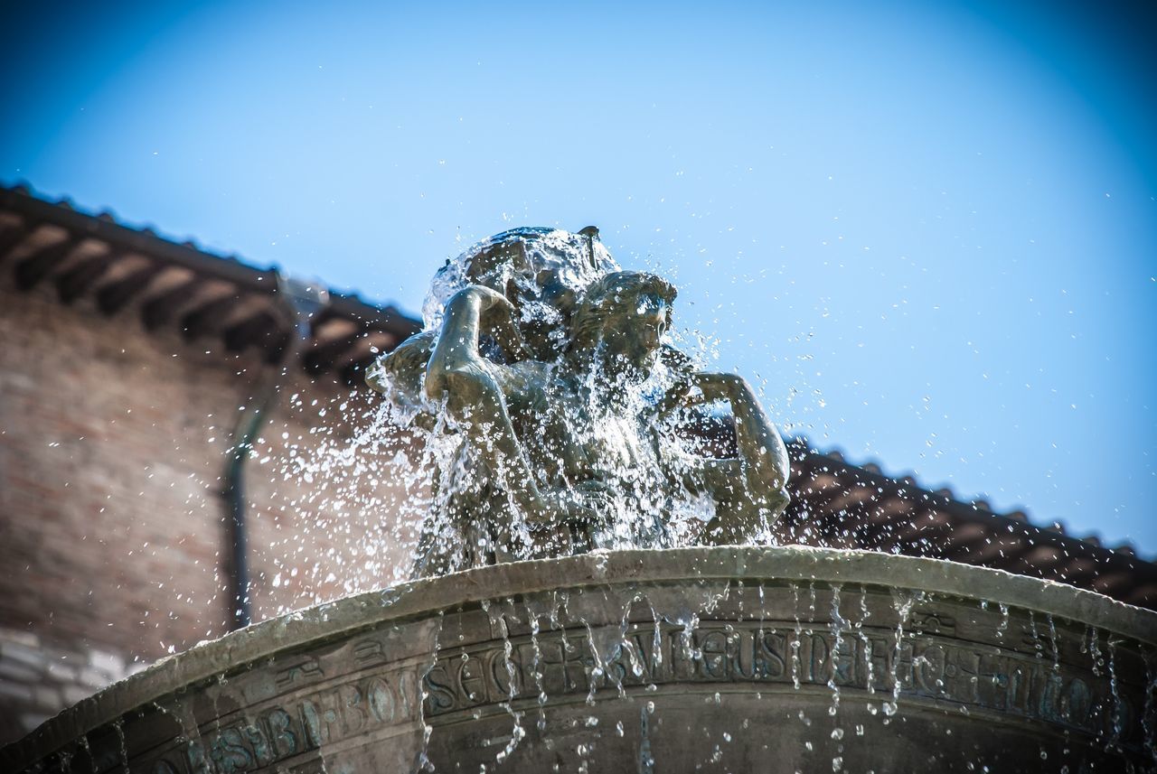 LOW ANGLE VIEW OF FOUNTAIN AGAINST BUILDINGS AGAINST CLEAR BLUE SKY