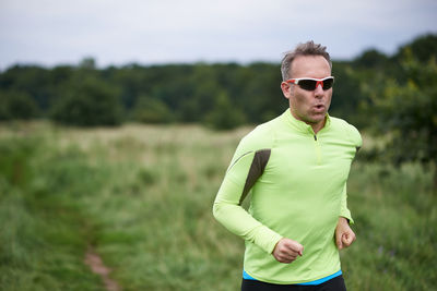 Man wearing sunglasses while jogging on field