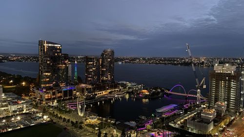 High angle view of illuminated city by sea against sky