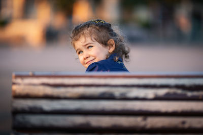 Close-up of girl looking away while sitting on bench