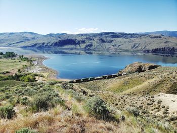 Scenic view of lake and mountains against clear blue sky