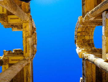 Directly below shot of old ruin aphrodite temple against clear blue sky