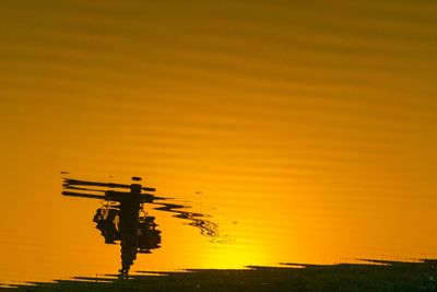 Silhouette crane against sky during sunset