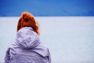 Rear view of woman in warm clothing against sky during winter
