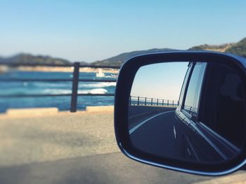 Close-up of side-view mirror against sky