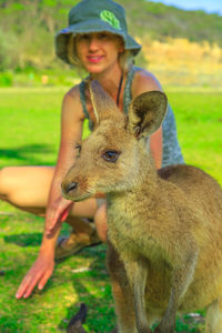 Portrait of cute girl with kangaroo on field