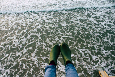 Low section of person standing in sea