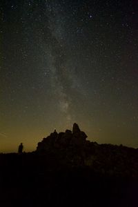 Low angle view of silhouette rock formation against sky at night