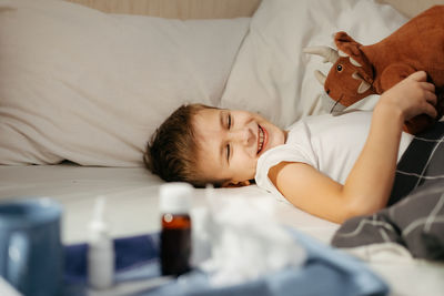 Happy child laying in bed in the morning. boy recovered from the illness.