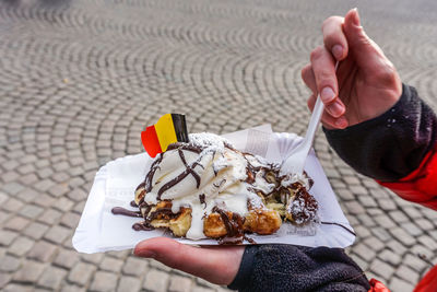 Cropped hands holding dessert over street