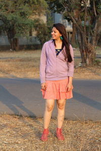 Full length of smiling young woman standing outdoors