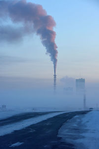 Smoke emitting from chimney against sky during winter