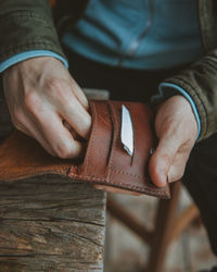 Midsection of man keeping cigarettes in leather wallet