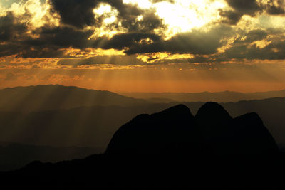 Scenic view of silhouette mountains against orange sky