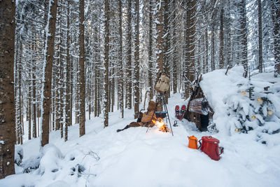 Austria, salzburg, altenmarkt-zauchensee, small wooden hut and campfire in forest covered with deep snow