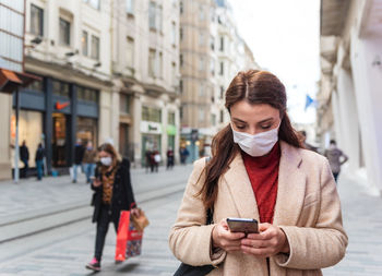 Full length of man using mobile phone on street