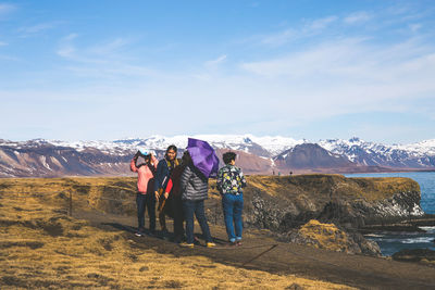 Rear view of people walking on mountain against sky