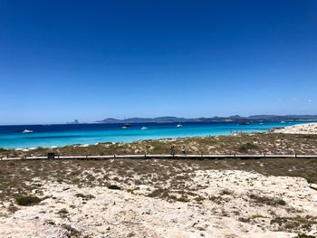 Scenic view of beach against clear blue sky