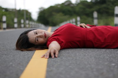 Rear view of woman lying on road
