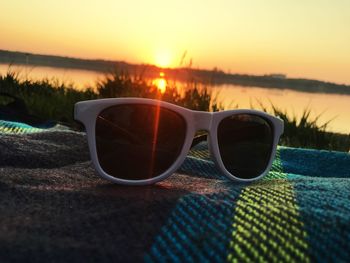 Close-up of sunglasses on beach during sunset
