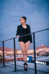 Portrait of woman standing by railing against sky