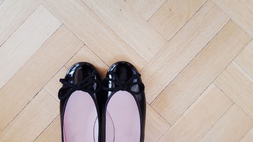 Low section of person wearing shoes on hardwood floor