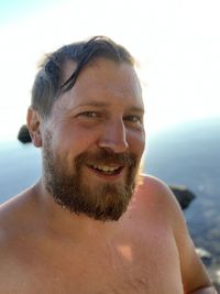 Portrait of a smiling bearded man with wet hair after a swim on a sunny day.