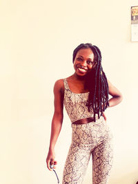 Portrait of smiling young woman standing against white background