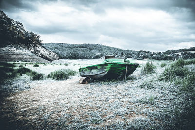 Abandoned boat moored on river against sky