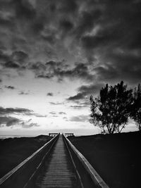 People walking on road against cloudy sky