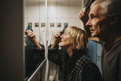 Senior couple brushing hair and doing make-up