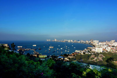 High angle view of buildings and sea against blue sky