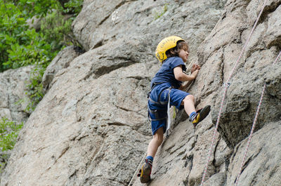 Full length of boy climbing cliff