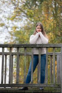 Woman standing against railing and fence in autumn