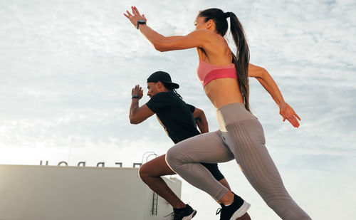 Side view of woman jumping against sky