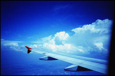 Close-up of airplane wing against cloudy sky