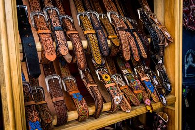 Cowboy boots and leather belts in a saddlery, footwear and accessories business showcase.