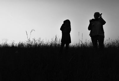 Woman with granddaughter on field against sky