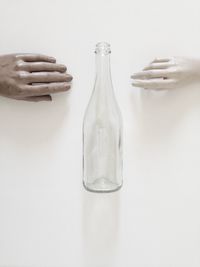 Figurine hand and bottle over white background