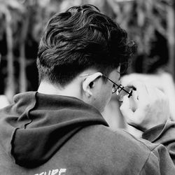 Rear view of man holding eyeglasses outdoors