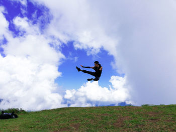 Man jumping on field against sky