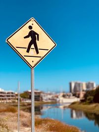 Road sign against clear blue sky