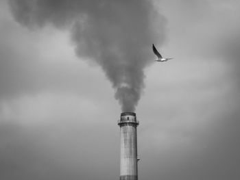 Low angle view of smoke emitting from chimney against sky