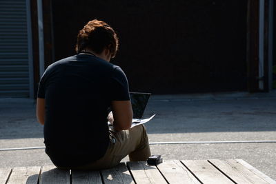 Rear view of a young man sitting on bench