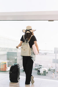 Rear view of women standing on airport against sky