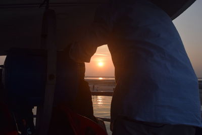 Close-up of human hand against sky during sunset