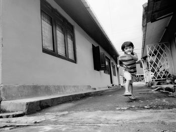 Boy running on footpath amidst buildings