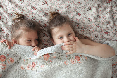 Sister's girls play and cuddle under a blanket, emotions. 