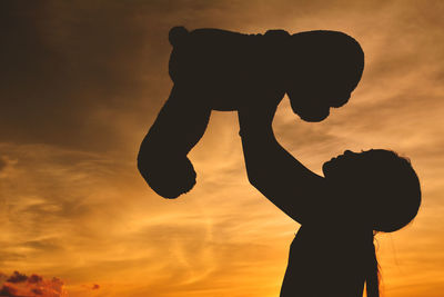 Silhouette of man against orange sky